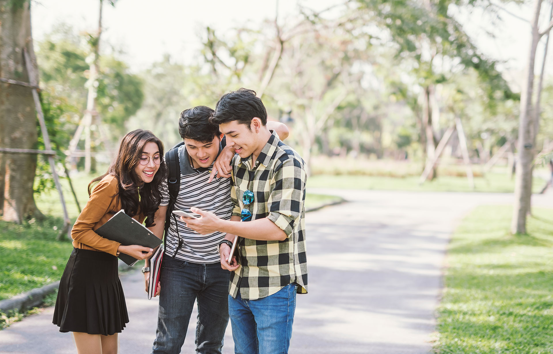 Sekelompok anak muda tersenyum melihat ponsel bersama